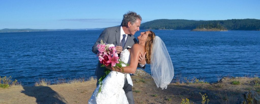 groom dipping his bride at the shoreline