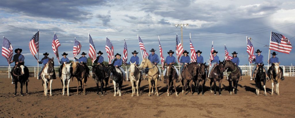 row of people on horseback holding american flags