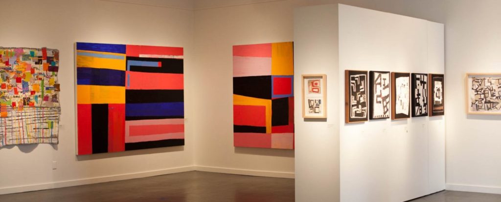 view of a gallery showing bright geometric paintings