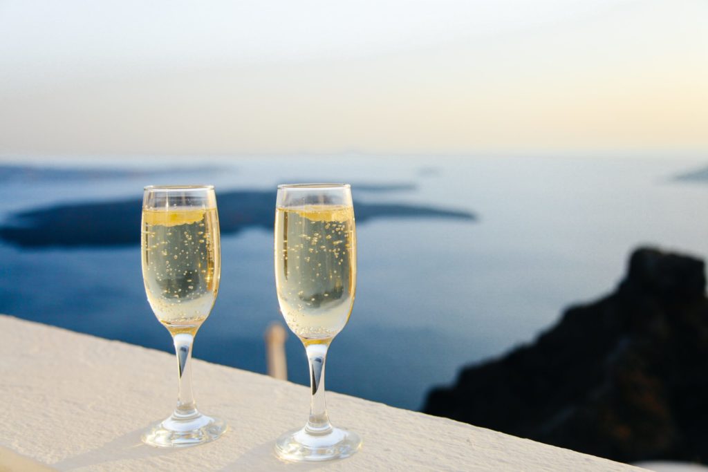 two glasses of champage on a ledge with the water in the distance