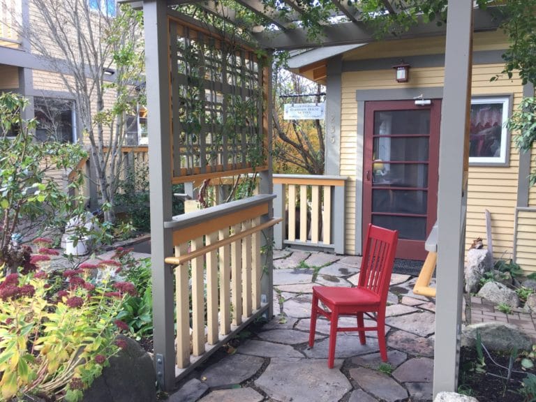 paved patio with a red wooden chair under an arbor