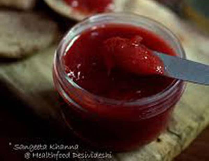 jar of red jam with a butter knife in it