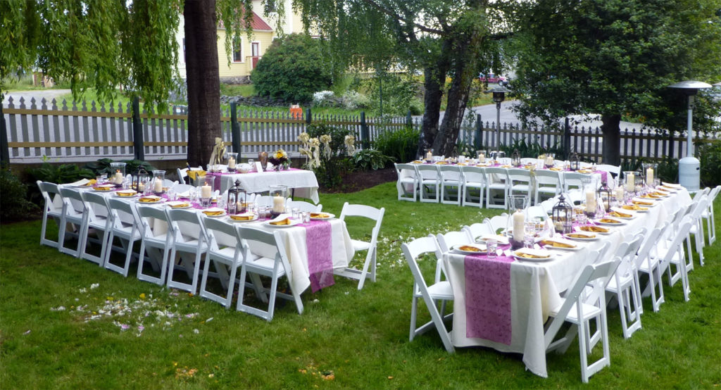 large white tables set up for a formal dinner in a garden