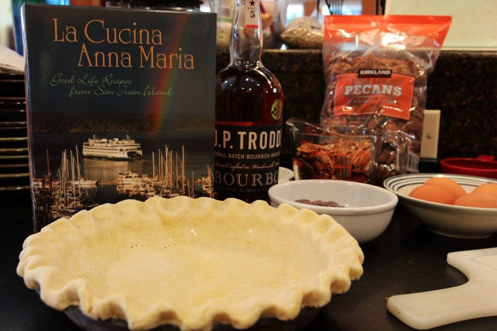 Unbaked pie shell and other ingreduents with a cookbook on a counter