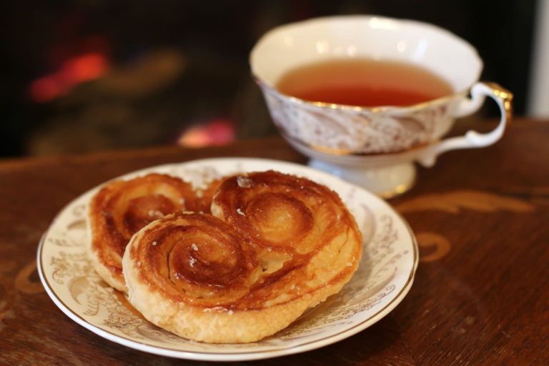 Two Palmiers on a small china plate and a cup of tea