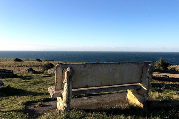 Concrete bench on a grassy hill with a view out over the water