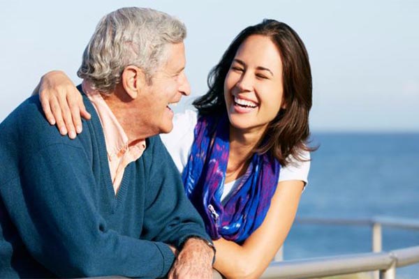 Older man and young woman laughing together at the railing of a boat
