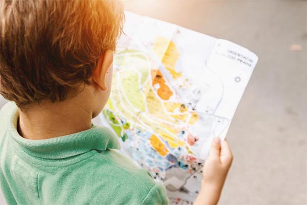child in a green polo reading a brightly colored map