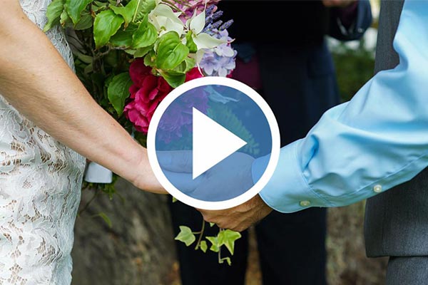 couple hlding hands with flower bouquet at back