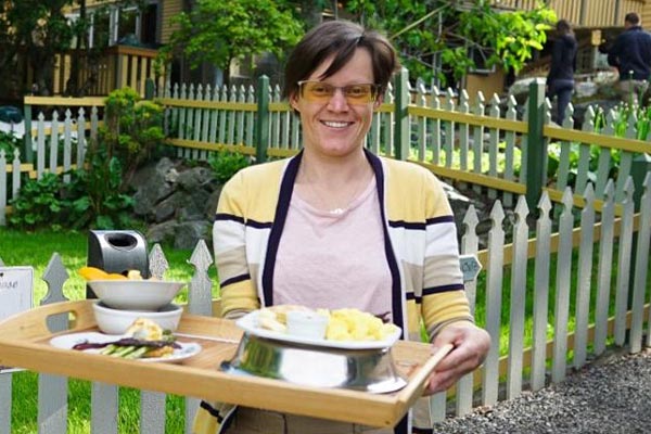 woman outside holding a tray stacked with breakfast items