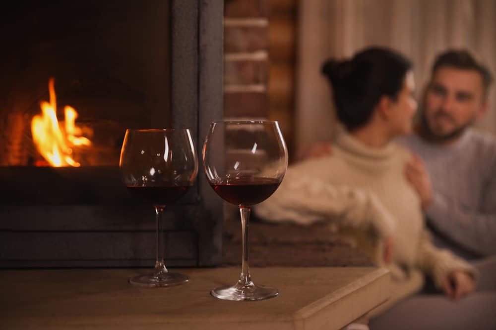 Romantic couple drinking wine by the fire during their romantic getaways in Washington State