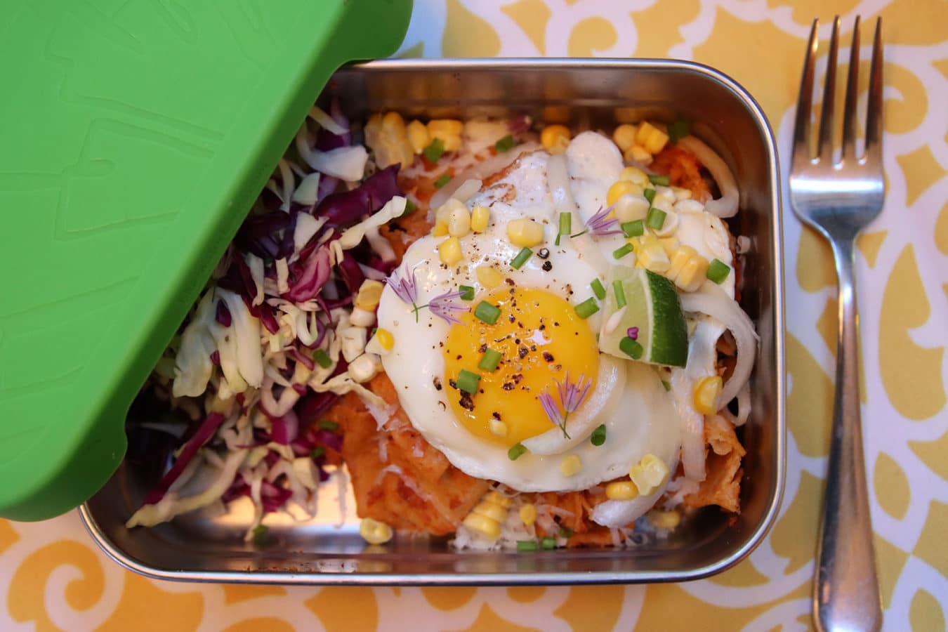 fork and steel box filled with cabbage slaw, corn, and a cooked egg