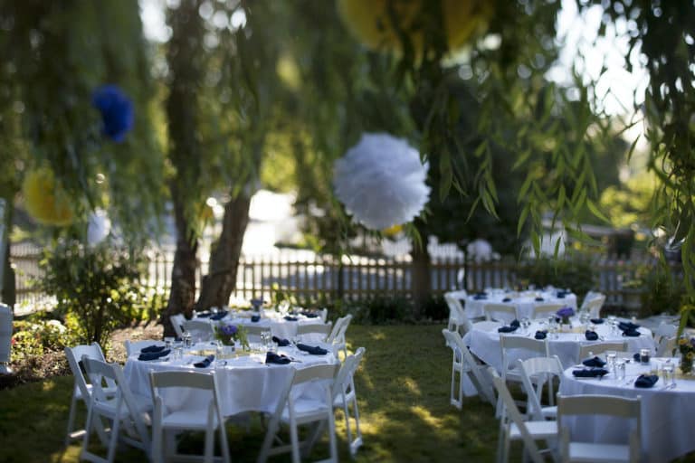 tables set in a lawn with white table clothes and chairs