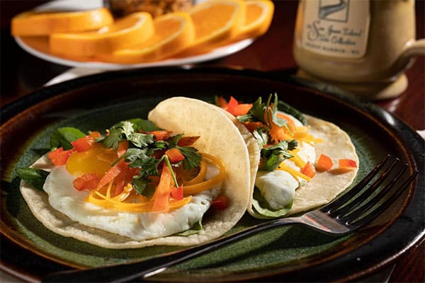 breakfast tacos with sliced oranges in the background