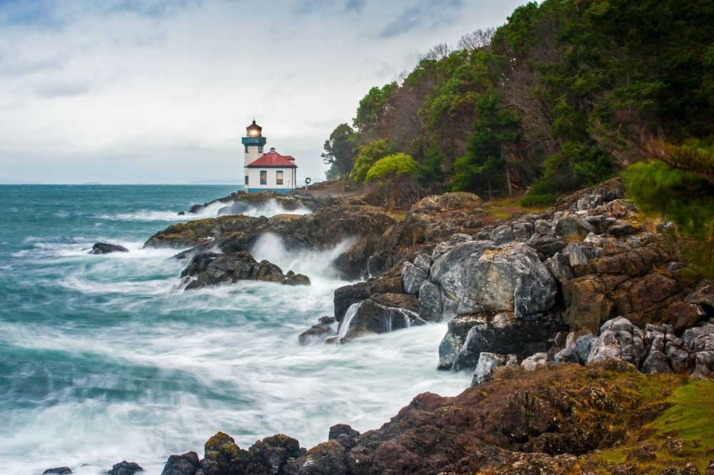 Lighthouse at a rocky shoreline with waves crashing in