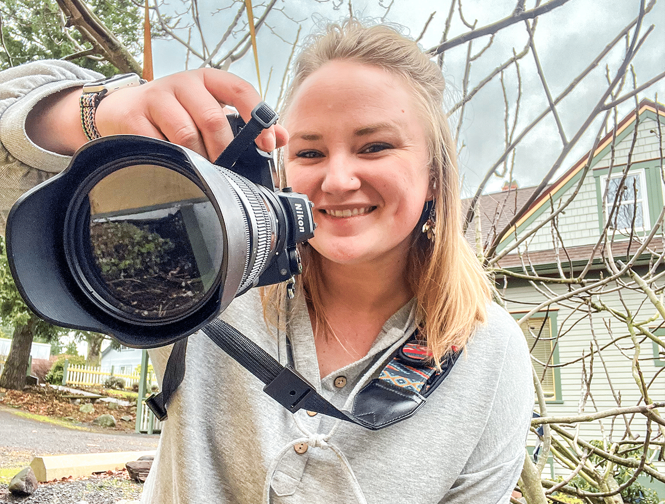 blonde woman holding a camera and smiling